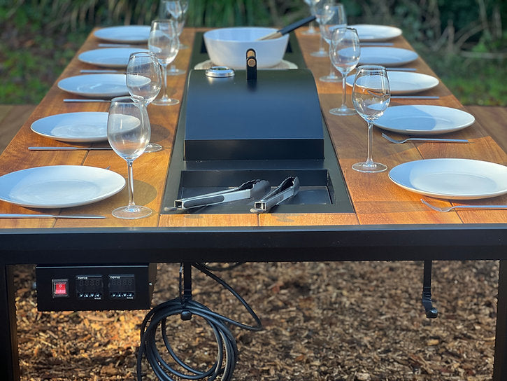 Outdoor dining setup with a portable grill on a wooden table.