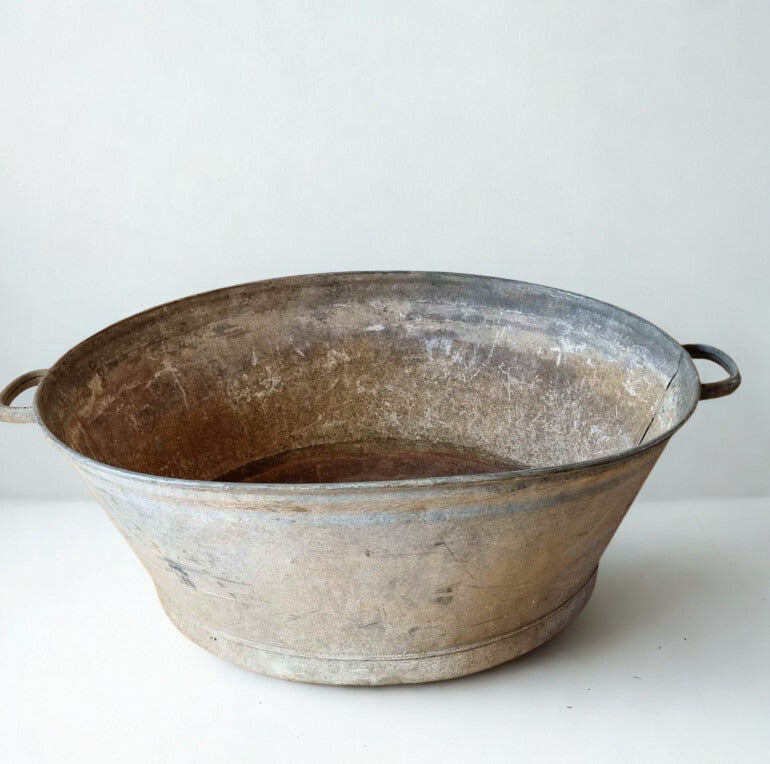 Vintage-style metal basin with handles on a white background
