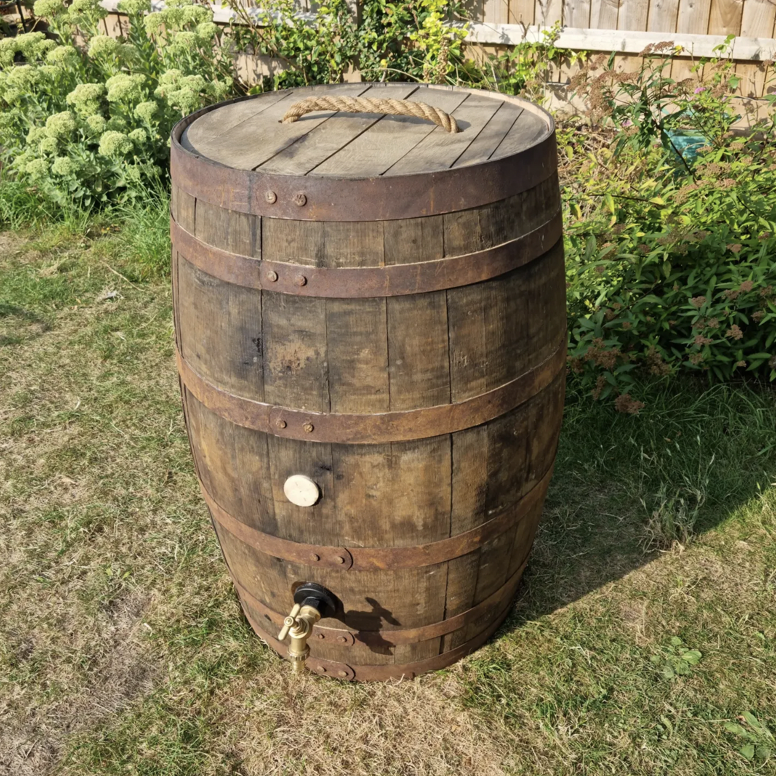 Wooden rain barrel with a hose bib on a grassy area