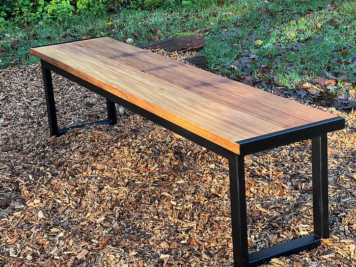 Wooden bench with metal legs on a mulched ground