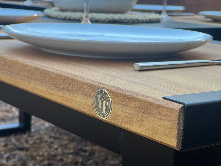 Wooden table with a metal logo and white plates in the background