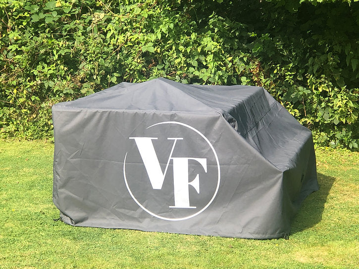 Gray outdoor furniture cover with 'VF' logo on a grassy area with greenery.